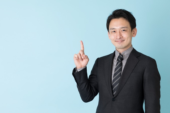 笑顔を指を差すスーツ男性
