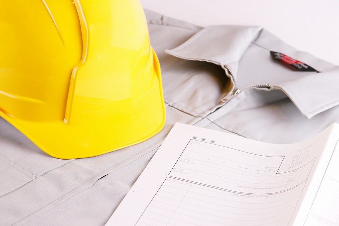 作業着の上に履歴書と黄色いヘルメット
