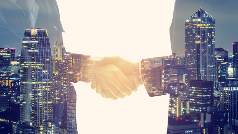 夜景を背景に握手する2人